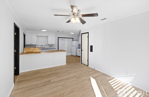 A modern kitchen with a wooden floor and a ceiling fan.