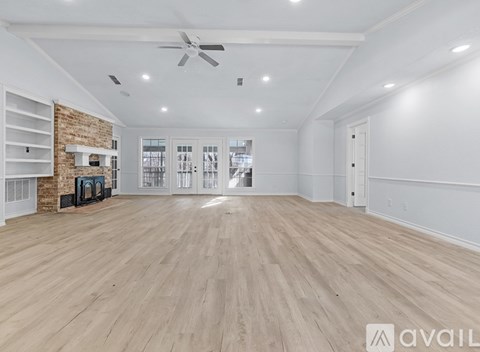 A spacious room with wooden flooring and a brick accent wall.