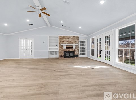 A spacious living room with a fireplace and a ceiling fan.
