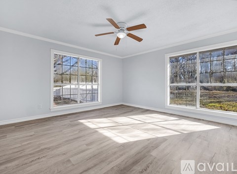 A room with a ceiling fan and two windows overlooking a snowy landscape.