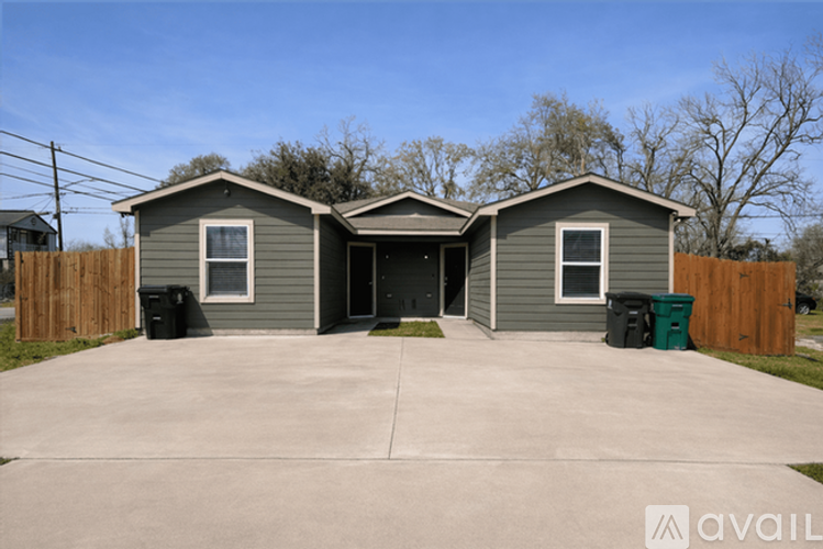 A house with a grey exterior and a black trash bin in front.
