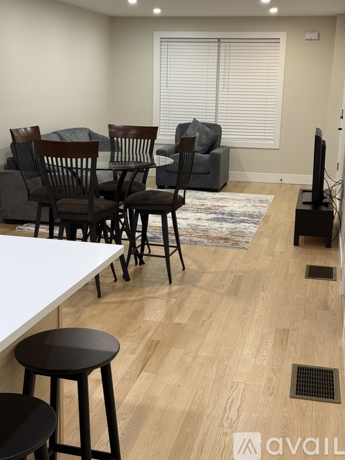 A living room with a white table, black chairs, and a TV.