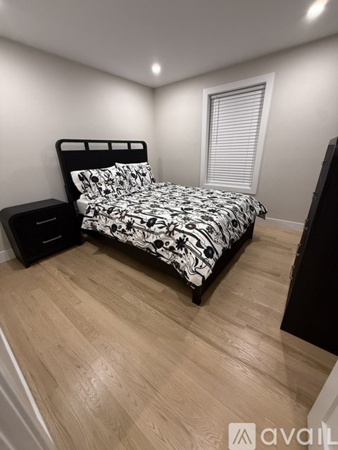 A bedroom with a bed, nightstand, and window with blinds.