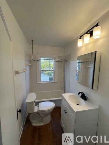 A bathroom with a toilet, sink, and mirror.