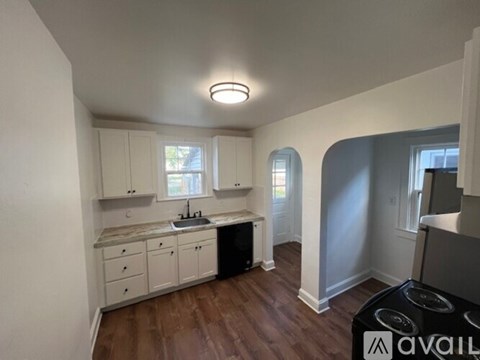 A kitchen with white cabinets and a wooden floor.
