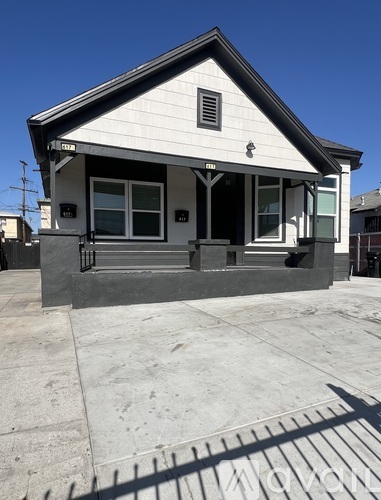 A small white house with a black roof and a black railing.