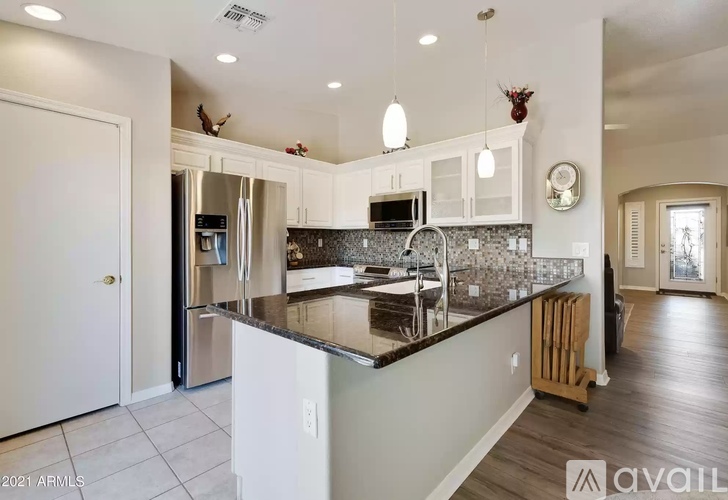 A kitchen with a black counter top and white cabinets.