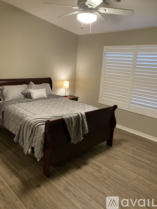 A bedroom with a bed, a ceiling fan, and a window with blinds.