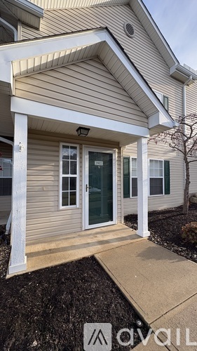 A house with a porch and a green door is for sale.