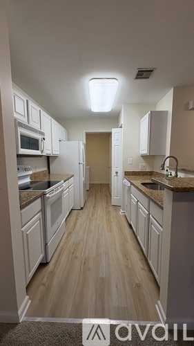 A kitchen with white cabinets and a wooden floor.