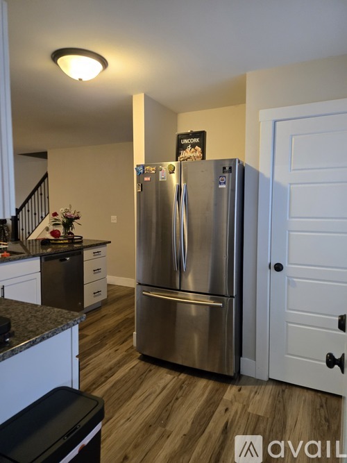 A stainless steel refrigerator in a kitchen with wooden floors.