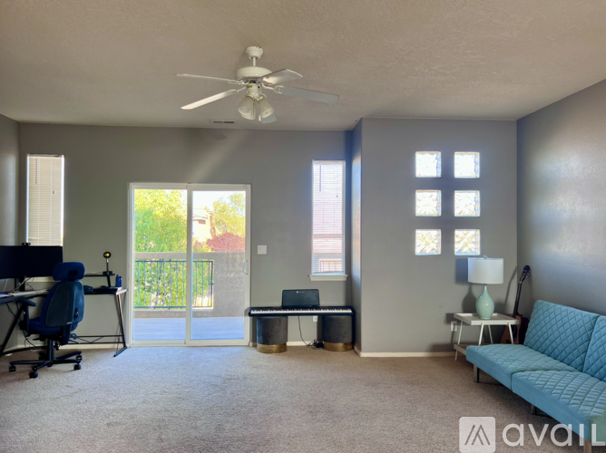 A living room with a blue couch and a ceiling fan.