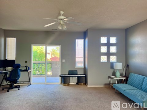 A living room with a blue couch and a ceiling fan.