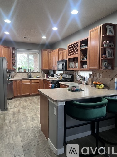 A kitchen with wooden cabinets and a counter with two green chairs.