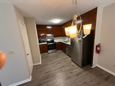A kitchen with a stainless steel refrigerator and wooden cabinets.