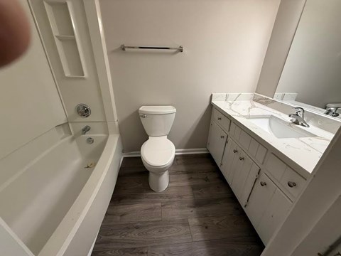 A white toilet sits in a bathroom next to a sink.