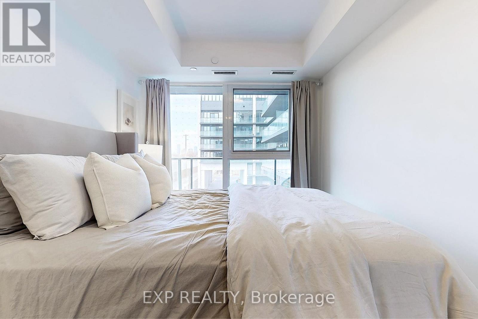A bedroom with a large bed and a view of the city through the window.