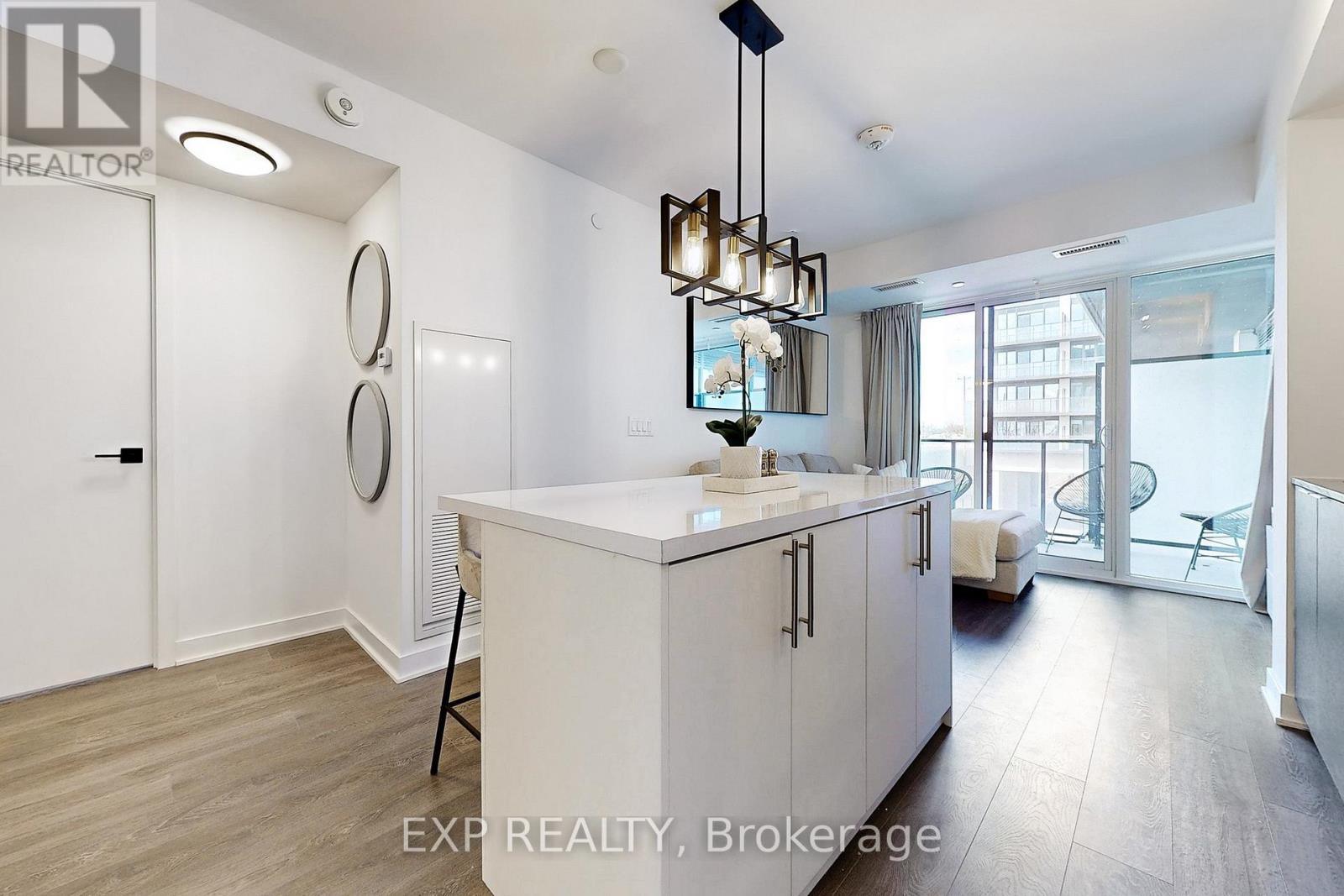 A modern kitchen with white cabinets and a wooden floor.