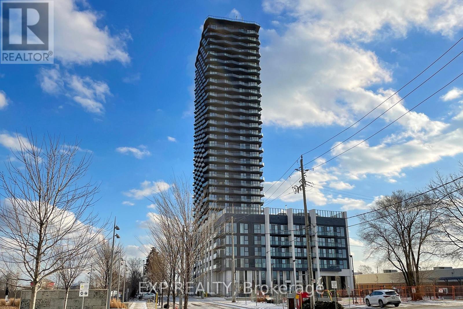 A tall building with a glass facade stands in the foreground of a cloudy sky.