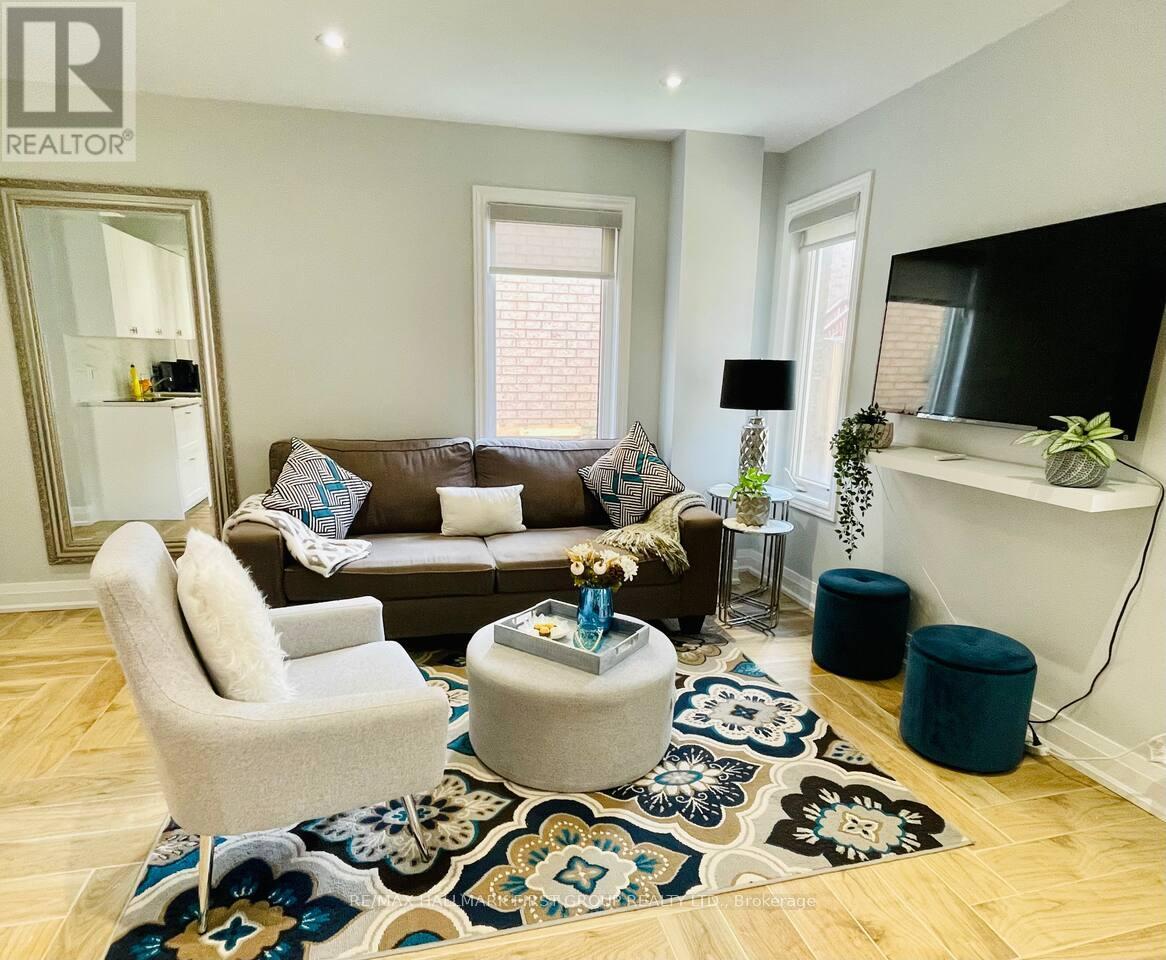 A living room with a brown couch, a grey armchair, and a patterned rug.