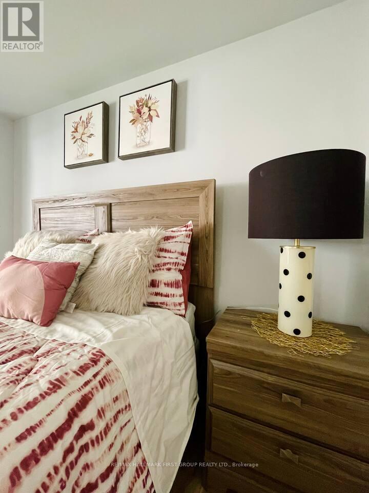 A bedroom with a bed, nightstand, and two framed pictures on the wall.
