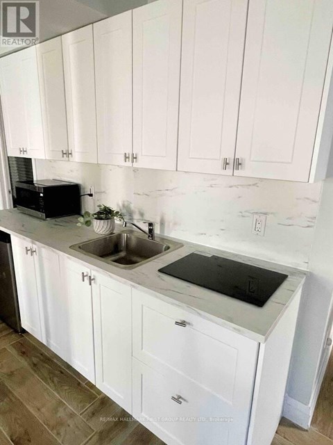 A kitchen with white cabinets and a black microwave.