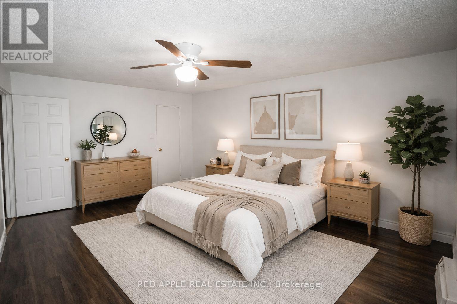 A bedroom with a bed, nightstands, and a ceiling fan.