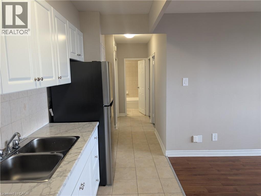 A kitchen with white cabinets and a black refrigerator.