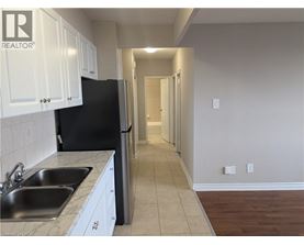 A kitchen with white cabinets and a black refrigerator.