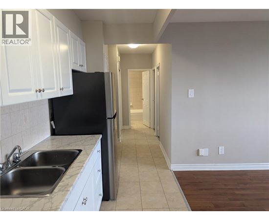 A kitchen with white cabinets and a black refrigerator.