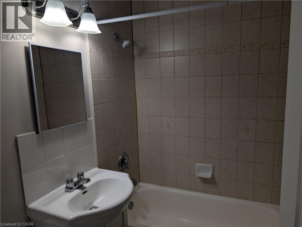 A bathroom with a sink, mirror, and bathtub.