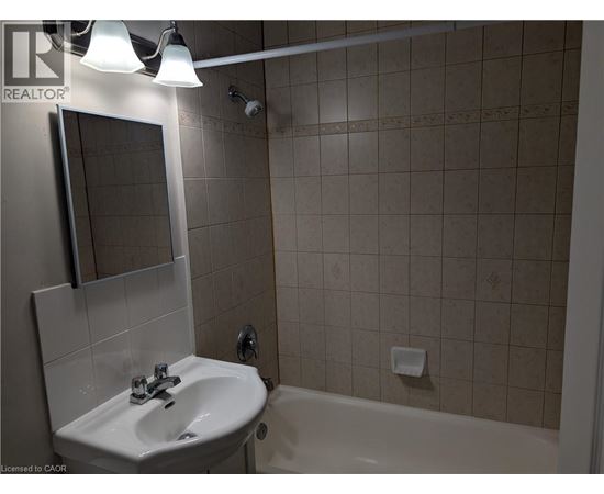 A bathroom with a sink, mirror, and bathtub.