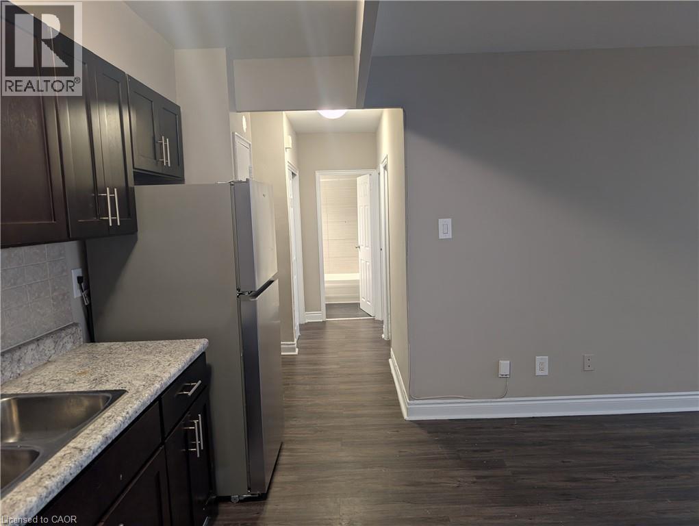 A kitchen with dark wood cabinets and a stainless steel refrigerator.