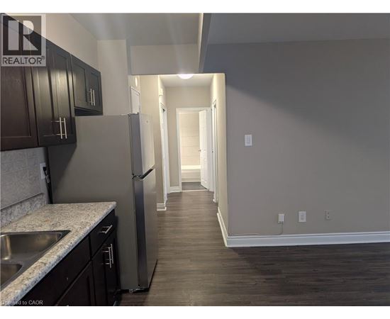A kitchen with dark wood cabinets and a stainless steel refrigerator.