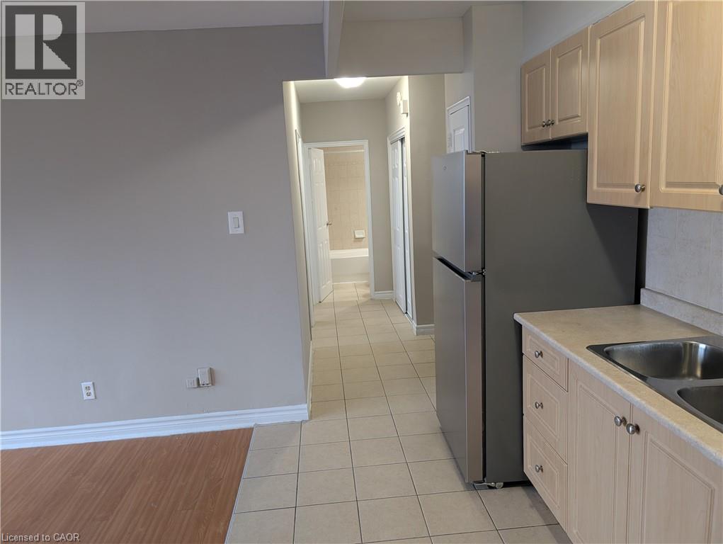A kitchen with a refrigerator, sink, and cabinets.