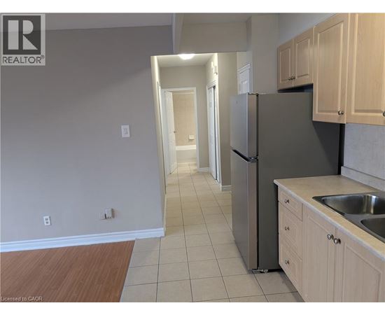A kitchen with a refrigerator, sink, and cabinets.