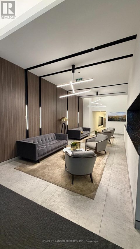 A modern living room with a grey sofa and a black and white rug.