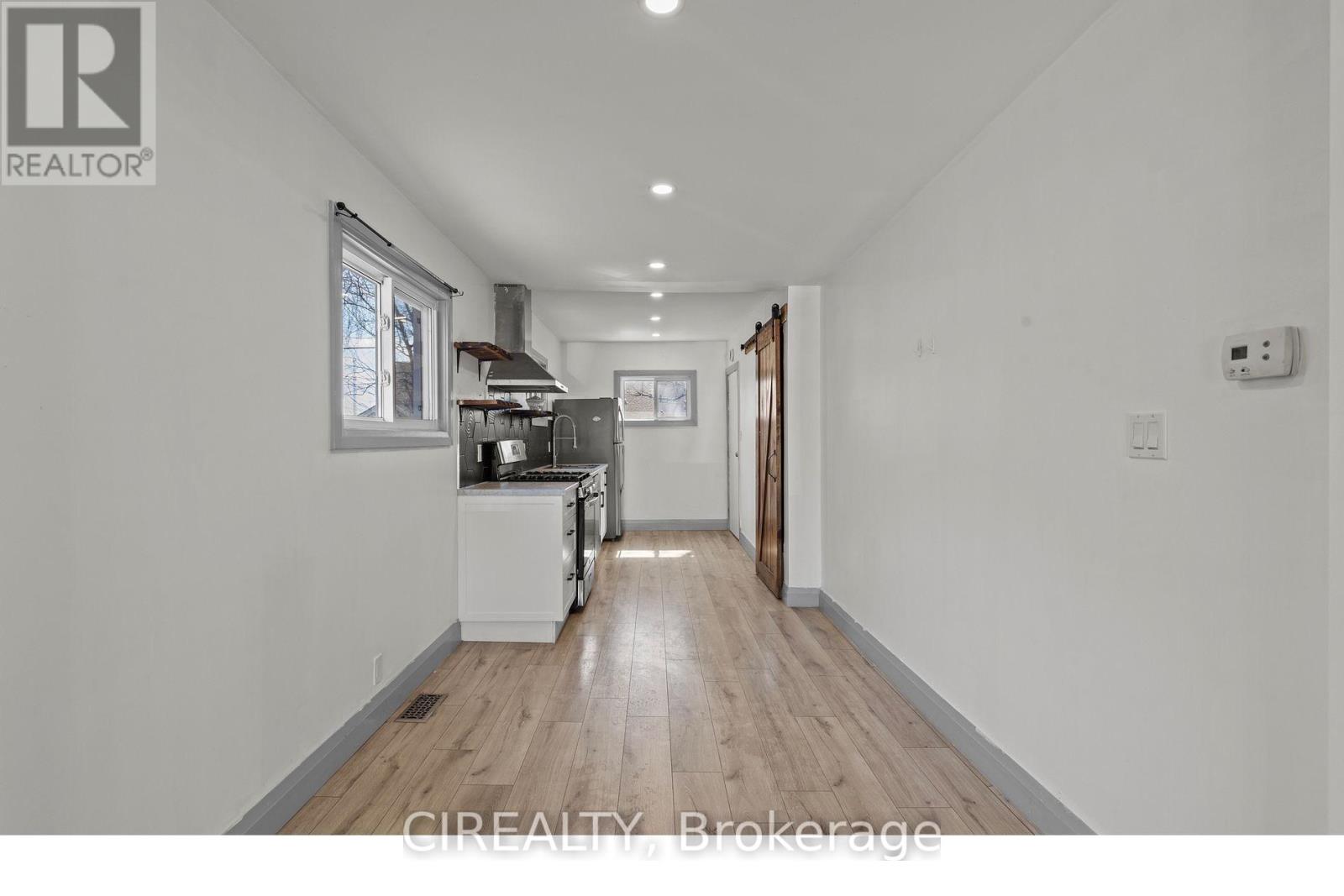 A well-lit, spacious kitchen with white appliances and wooden flooring.