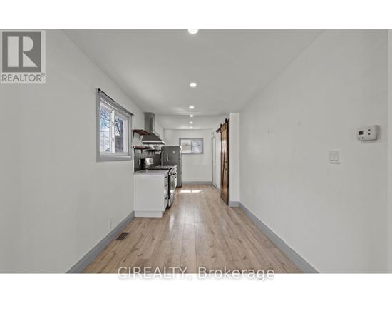 A well-lit, spacious kitchen with white appliances and wooden flooring.