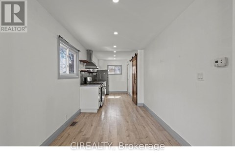 A well-lit, spacious kitchen with white appliances and wooden flooring.