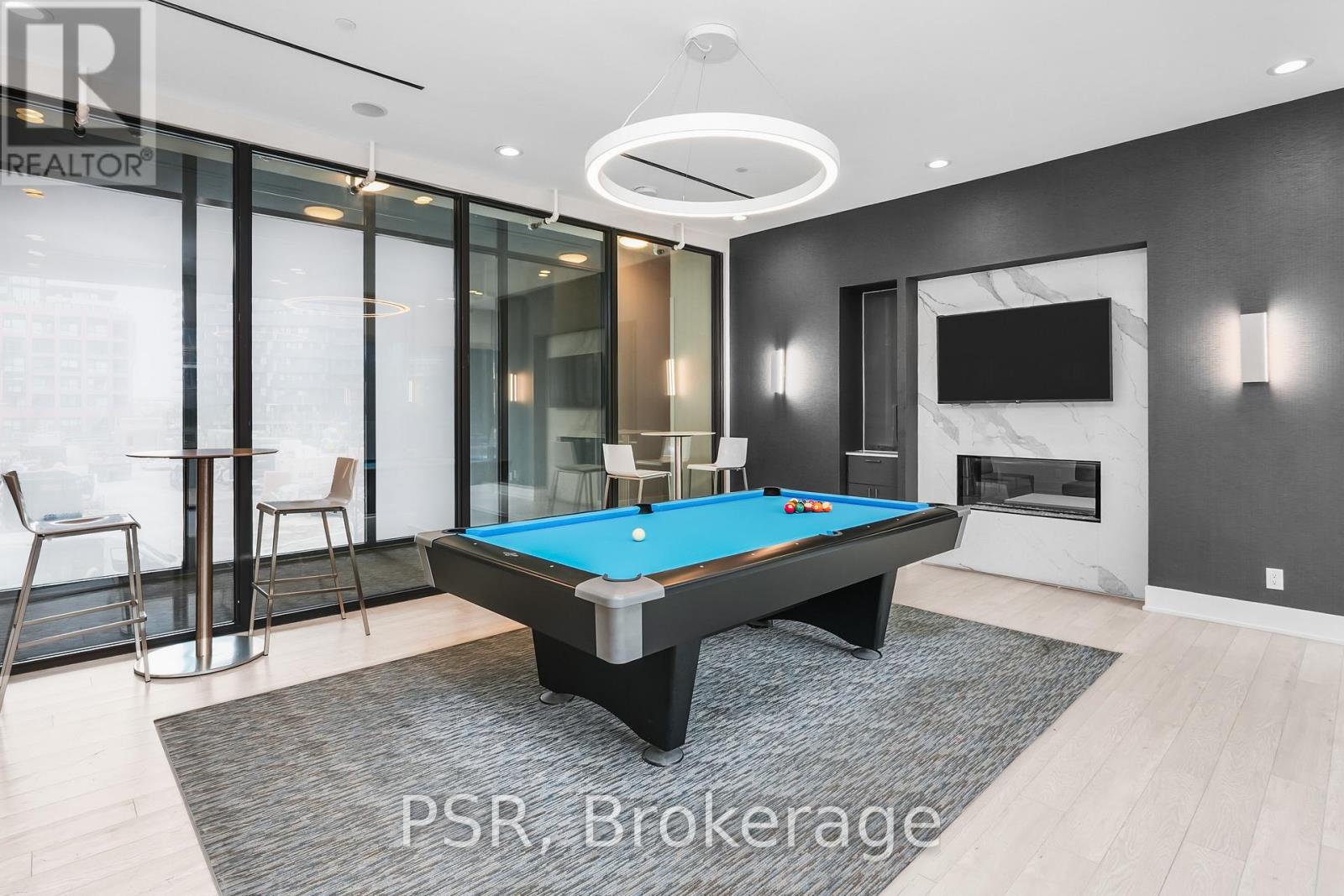 A pool table in a room with a fireplace and a TV.