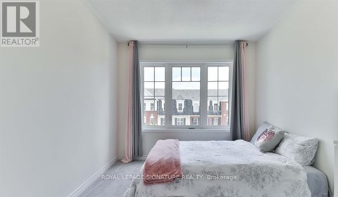 A bedroom with a bed, pillows, and a window overlooking a street.