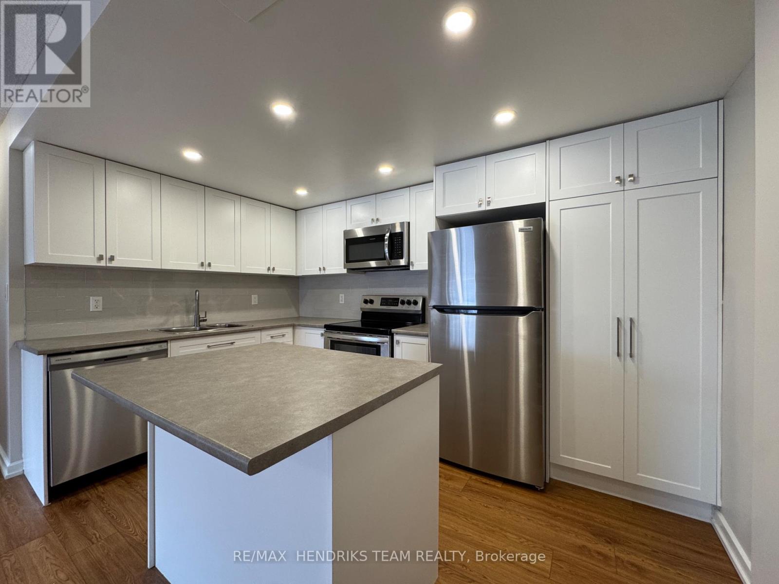 A kitchen with white cabinets and a stainless steel refrigerator.