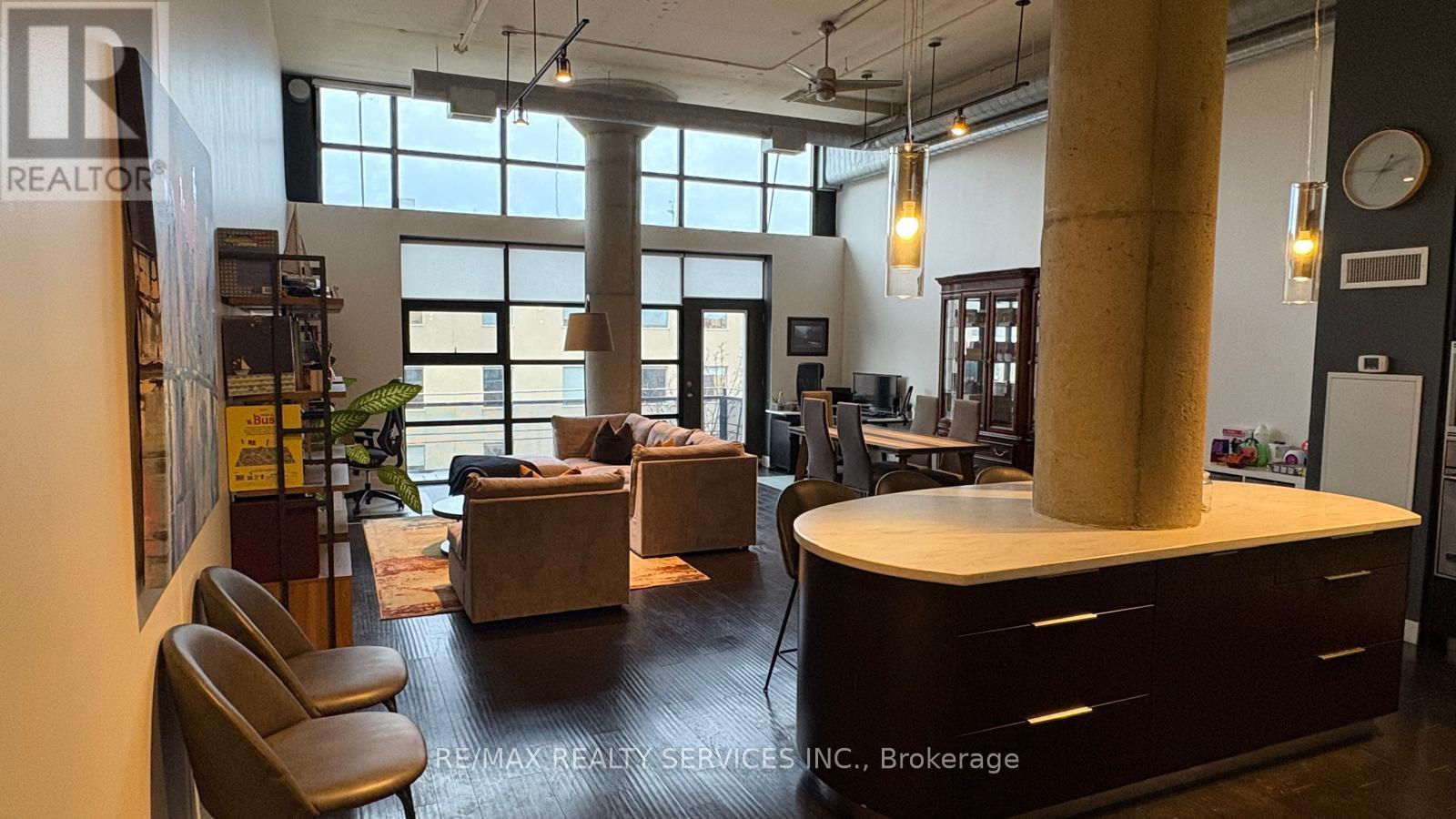 A modern office space with a large window, a desk, and a couch.