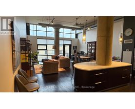 A modern office space with a large window, a desk, and a couch.