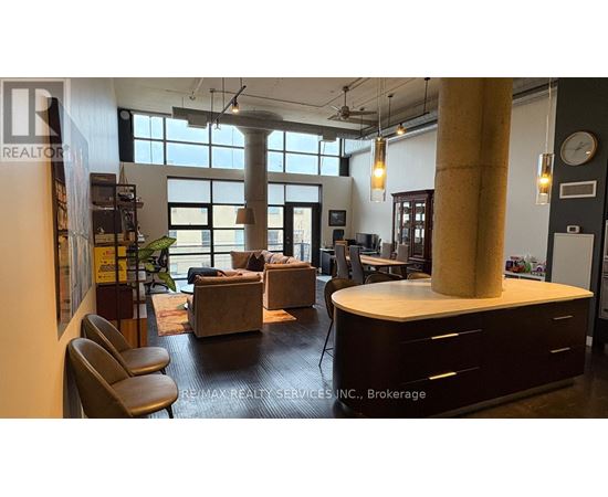 A modern office space with a large window, a desk, and a couch.
