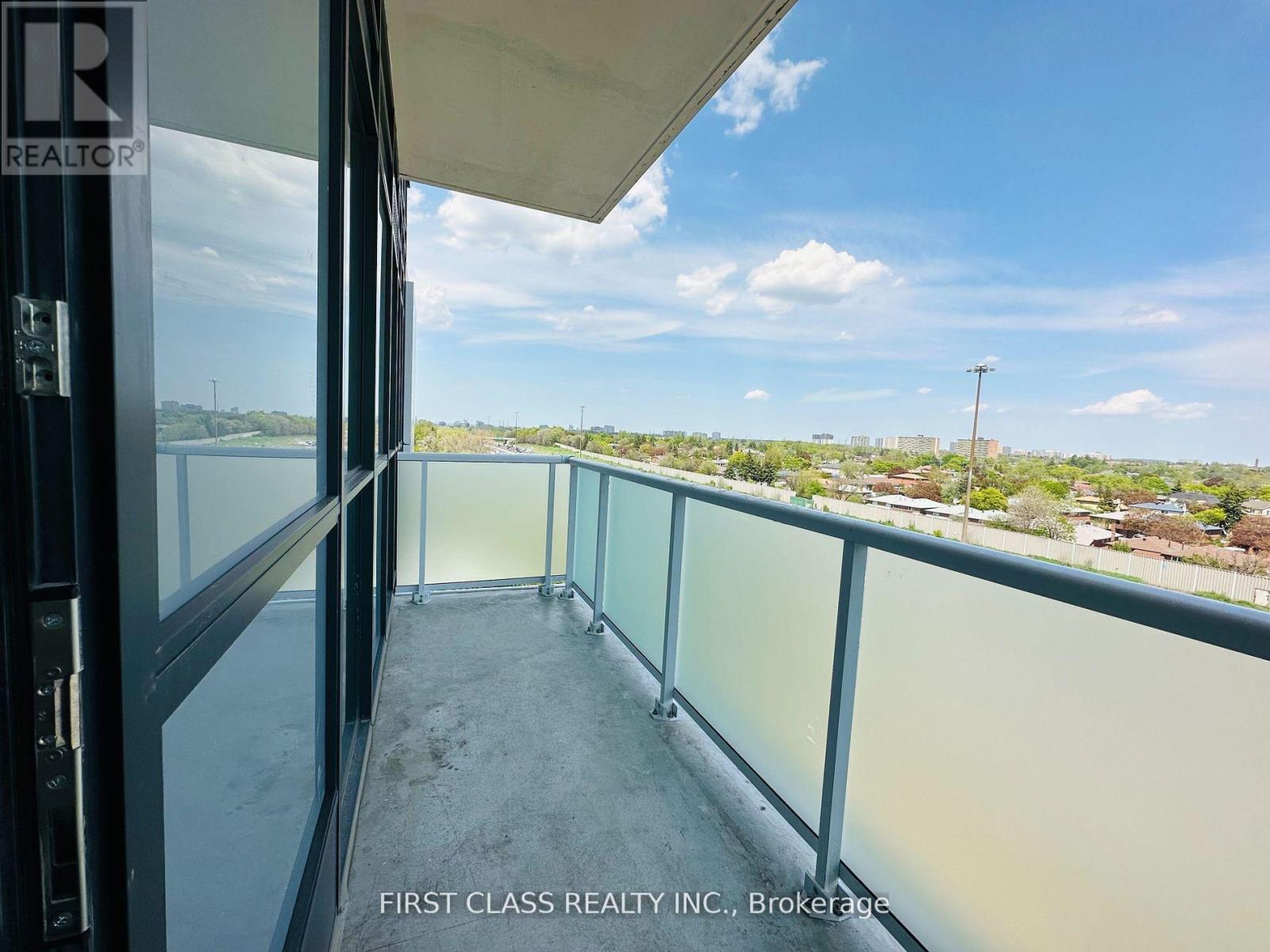 A balcony with a glass railing and a view of the city.