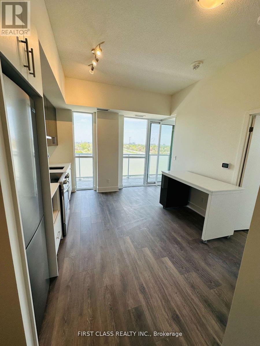 A kitchen with a refrigerator, sink, and a dining table with chairs.