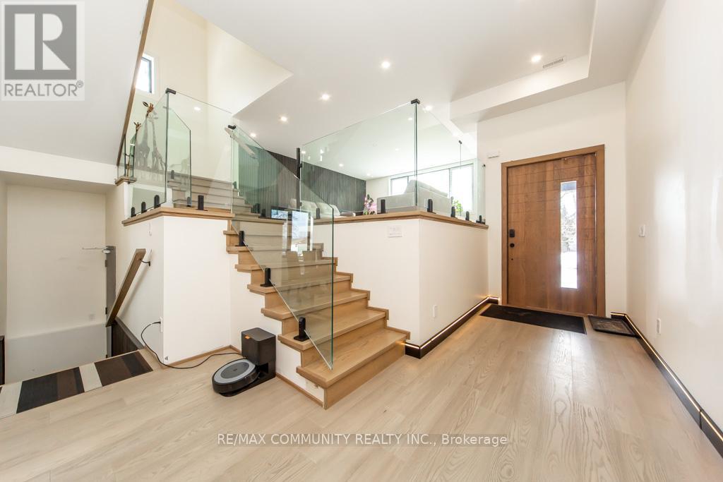 A spacious room with a glass railing staircase and a wooden door.