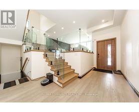 A spacious room with a glass railing staircase and a wooden door.
